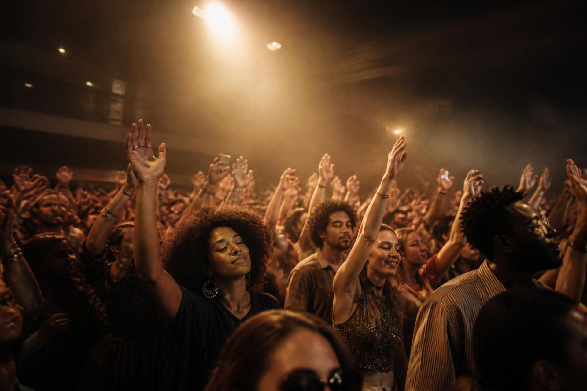 A crowd with hands raised under warm stage light at a Social Made style experience